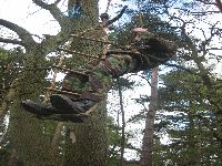 A cadet being hoisted up to collect a rope at the end of the natural assault course